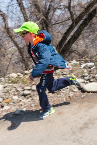 Alma-Ata, Kazachstan--09 April 2017: Amateur competities - berg halve marathon, in de uitlopers van Almaty, op de Yunat-meren. Gelukkig jongetje naar huis van school gaan — Stockfoto