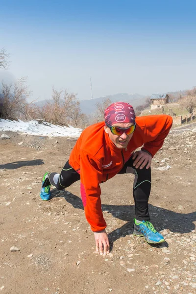 Alma-Ata, Kazachstan--09 April 2017: Amateur competities - berg halve marathon, in de uitlopers van Almaty, op de Yunat-meren. Portret van een mannelijke atleet warming-up en stretching — Stockfoto