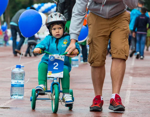 Kazachstan, Alma-Ata - 11 juni 2017: Childrens wedstrijden fietsen Tour de kinderen. Kinderen van 2 tot en met 7 jaar oud concurreren in het stadion en prijzen ontvangen. Een kleine jongen een fiets rijdt en concurreert om te worden — Stockfoto