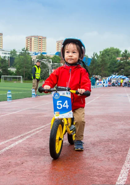 Kazachstan, Alma-Ata - 11 juni 2017: Childrens wedstrijden fietsen Tour de kinderen. Kinderen van 2 tot en met 7 jaar oud concurreren in het stadion en prijzen ontvangen. Het meisje op een fiets rijdt op een sportstadion — Stockfoto