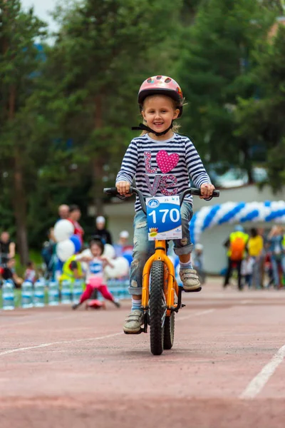 Kazachstan, Alma-Ata - 11 juni 2017: Childrens wedstrijden fietsen Tour de kinderen. Kinderen van 2 tot en met 7 jaar oud concurreren in het stadion en prijzen ontvangen. Het meisje op een fiets rijdt op een sportstadion — Stockfoto
