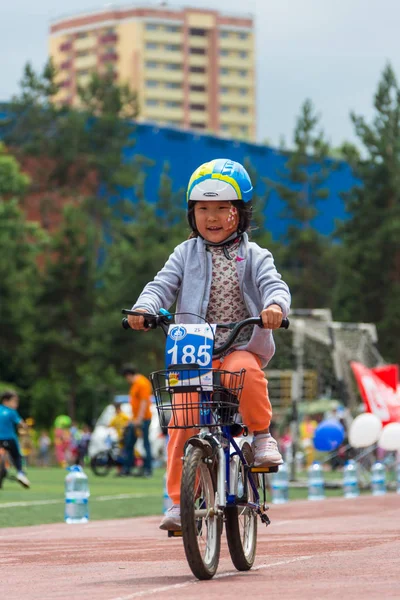 Kazakistan, Almaty - 11 Haziran 2017: yarışmalar Bisiklete binme çocuk de çocuklar tur. 2 ile 7 yaş arası çocuklar stadyumda rekabet ve ödüller alırsınız. Bir spor stadyum üzerinde kız bir bisiklet sürmek