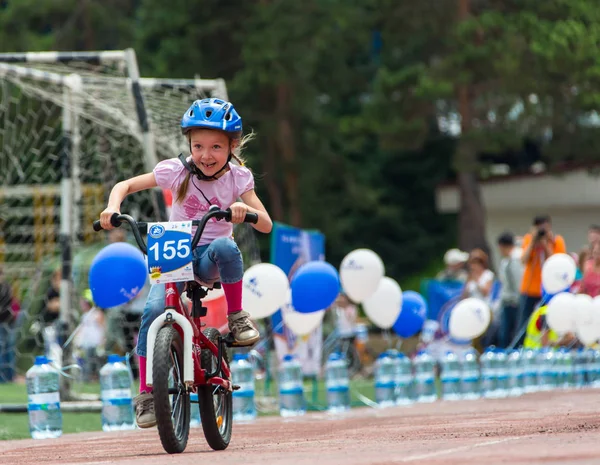 KAZAKHSTAN, ALMATY - 11 de junio de 2017: Concursos de ciclismo infantil Tour de kids. Los niños de 2 a 7 años compiten en el estadio y reciben premios. La chica en bicicleta monta en un estadio deportivo — Foto de Stock