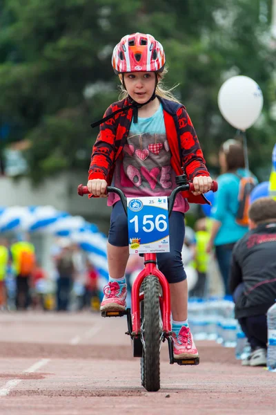Kazachstan, Almaty - 11 czerwca 2017 r.: Dla dzieci zawody rowerowe Tour de dzieci. Dzieci w wieku od 2 do 7 lat konkurować na stadionie i otrzymać nagrody. Dziewczyna na rowerze jeździ na stadion sportowy — Zdjęcie stockowe