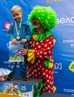 Kazakistan, Almaty - 11 Haziran 2017: yarışmalar Bisiklete binme çocuk de çocuklar tur. 2 ile 7 yaş arası çocuklar stadyumda rekabet ve ödüller alırsınız. Küçük kız ve palyaço avuç içi oynamak.