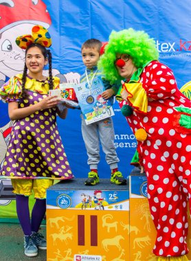 Kazakistan, Almaty - 11 Haziran 2017: yarışmalar Bisiklete binme çocuk de çocuklar tur. 2 ile 7 yaş arası çocuklar stadyumda rekabet ve ödüller alırsınız. Küçük kız ve palyaço avuç içi oynamak.