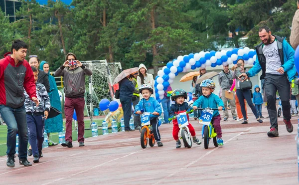 KAZAKHSTAN, ALMATY - 11 de junio de 2017: Concursos de ciclismo infantil Tour de kids. Los niños de 2 a 7 años compiten en el estadio y reciben premios. Retrato de tres pequeños ciclistas montando su — Foto de Stock