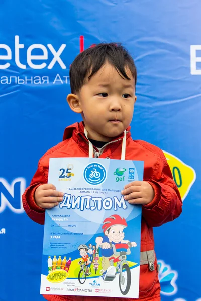 KAZAKHSTAN, ALMATY - 11 JUIN 2017 : Compétitions cyclistes pour enfants Tour de kids. Les enfants âgés de 2 à 7 ans concourent dans le stade et reçoivent des prix. excité garçon et filles avec des médailles — Photo