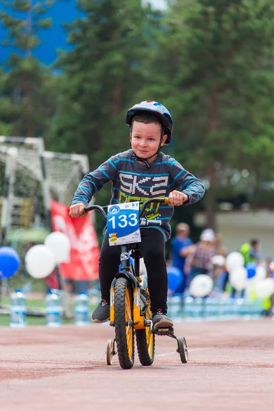 Kazachstan, Alma-Ata - 11 juni 2017: Childrens wedstrijden fietsen Tour de kinderen. Kinderen van 2 tot en met 7 jaar oud concurreren in het stadion en prijzen ontvangen. Portret van een leuke jongen op fiets — Stockfoto