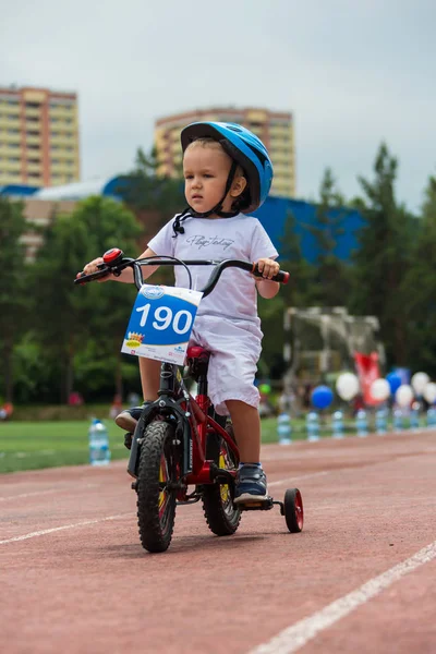 Kazachstan, Alma-Ata - 11 juni 2017: Childrens wedstrijden fietsen Tour de kinderen. Kinderen van 2 tot en met 7 jaar oud concurreren in het stadion en prijzen ontvangen. Portret van een leuke jongen op fiets — Stockfoto