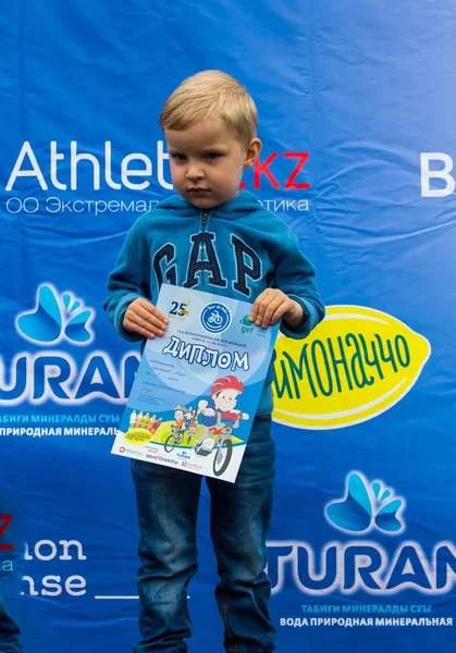 KAZAKHSTAN, ALMATY - JUNE 11, 2017: Childrens cycling competitions Tour de kids. Children aged 2 to 7 years compete in the stadium and receive prizes. Excited boy and girls with medals — Stock Photo, Image