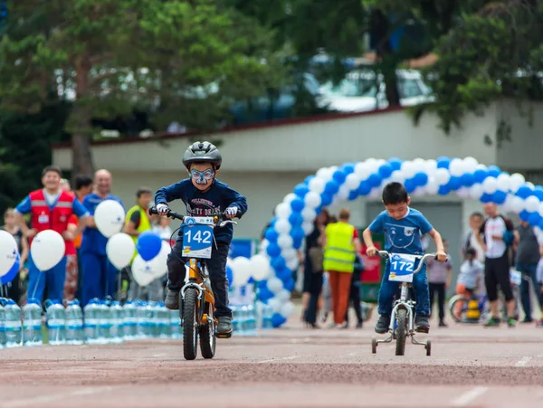 KAZAKHSTAN, ALMATY - JUNE 11, 2017: Childrens cycling competitions Tour de kids. Children aged 2 to 7 years compete in the stadium and receive prizes. Portrait of three little cyclists riding their — Stock Photo, Image