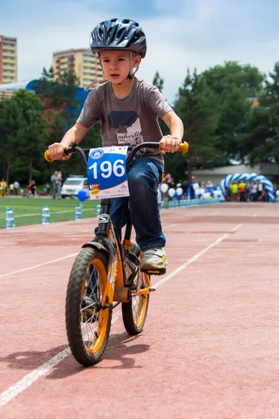 Kazachstan, Alma-Ata - 11 juni 2017: Childrens wedstrijden fietsen Tour de kinderen. Kinderen van 2 tot en met 7 jaar oud concurreren in het stadion en prijzen ontvangen. Portret van een leuke jongen op fiets — Stockfoto