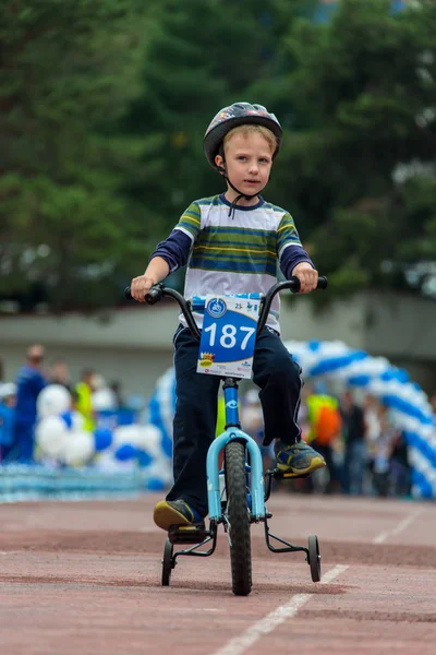 Kazachstan, Alma-Ata - 11 juni 2017: Childrens wedstrijden fietsen Tour de kinderen. Kinderen van 2 tot en met 7 jaar oud concurreren in het stadion en prijzen ontvangen. Portret van een leuke jongen op fiets — Stockfoto