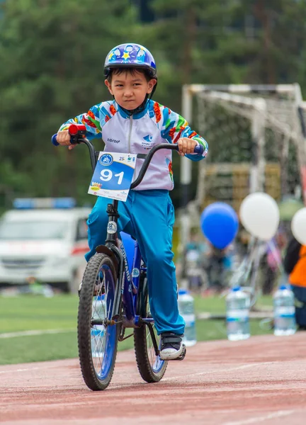 Kazachstan, Alma-Ata - 11 juni 2017: Childrens wedstrijden fietsen Tour de kinderen. Kinderen van 2 tot en met 7 jaar oud concurreren in het stadion en prijzen ontvangen. Portret van een leuke jongen op fiets — Stockfoto