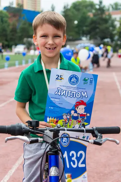 KAZAKHSTAN, ALMATY - 11 de junio de 2017: Concursos de ciclismo infantil Tour de kids. Los niños de 2 a 7 años compiten en el estadio y reciben premios. chico emocionado y las niñas con medallas — Foto de Stock