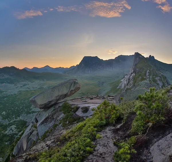 Opknoping stenen ligt op hellende oppervlak van berg boven de afgrond. Een enorme blok van graniet en syeniet wordt ondersteund door een klein gebied op berg. Ergaki Park. Rusland — Stockfoto