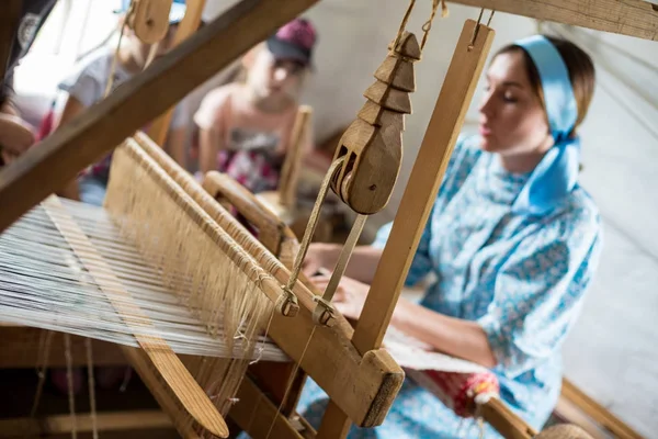 A mulher está tecendo o manto de algodão colorido ou vestido usando tear de madeira na aldeia local na Rússia — Fotografia de Stock