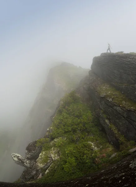 女孩旅行者爬上山顶, 坐着看日落和雾. — 图库照片