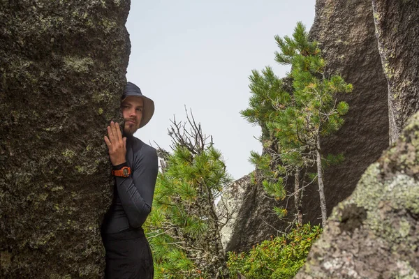 Männlicher Bergsteiger. Bergsteiger klettert auf eine schwarze Felswand am Ufer des Ozeans in Island, am Strand von Kirkjufjara. Mann macht schweren Schritt ohne Seil. — Stockfoto