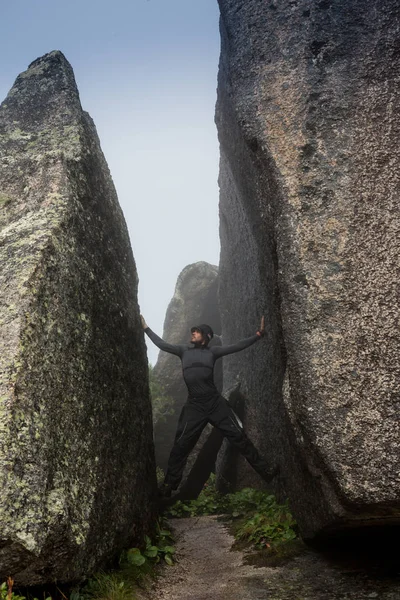 Hombre escalador de roca. escalador escalada en una pared rocosa negro en la orilla del océano en Islandia, playa de Kirkjufjara. hombre hace movimiento duro sin cuerda . —  Fotos de Stock