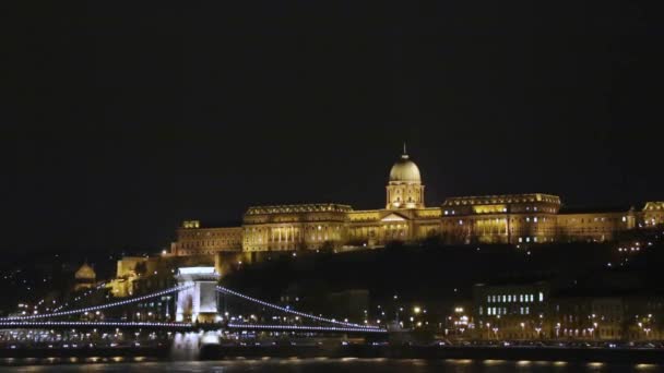 Osvětlené Szechenyi most a královský palác na kopci Budína Budapešti záběry - Řetězový most v maďarském hlavním městě Budapešti osvětlené v noci — Stock video