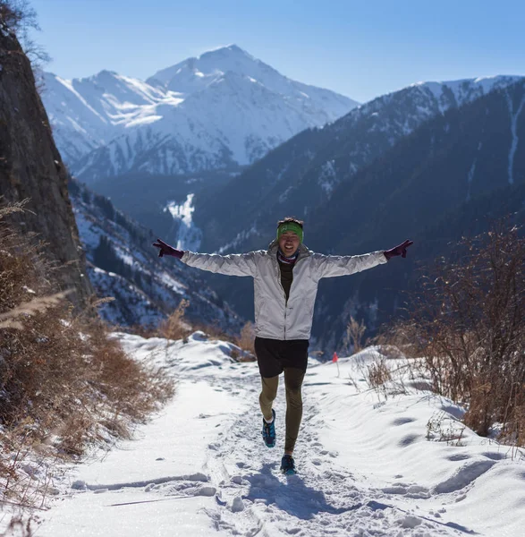 ALMATY, KAZAKHSTAN - 09 AVRIL 2017 : Compétitions amateurs - Demi-marathon de montagne, au pied d'Almaty, sur les lacs Yunat. .Athlete homme courant avec des montagnes en hiver — Photo