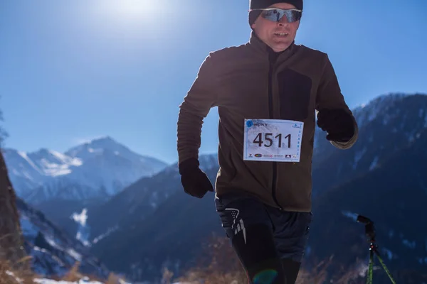 ALMATY, KAZAKHSTAN - 09 DE ABRIL DE 2017: Competiciones de aficionados - Media maratón de montaña, en las estribaciones de Almaty, en los lagos de Yunat. .Athlete hombre corriendo con montañas en invierno — Foto de Stock