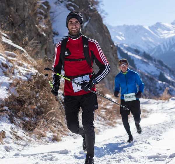 ALMATY, KAZAKHSTAN - 09 DE ABRIL DE 2017: Competiciones de aficionados - Media maratón de montaña, en las estribaciones de Almaty, en los lagos de Yunat. Grupo de personas corriendo en invierno — Foto de Stock