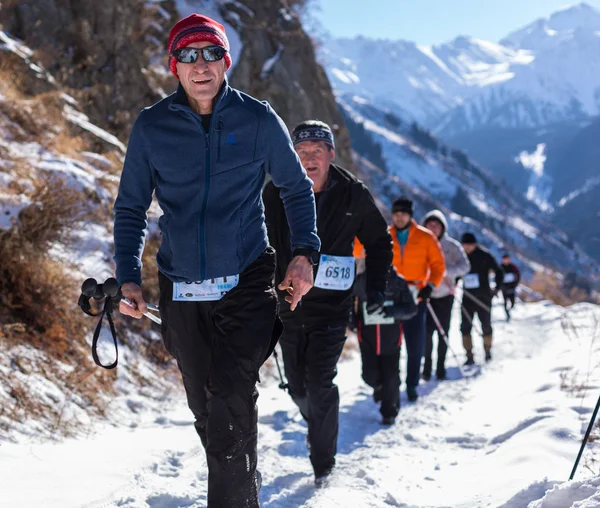 ALMATY, KAZAKHSTAN - APRIL 09, 2017: Kompetisi amatir - setengah maraton gunung, di kaki bukit Almaty, di danau Yunat. Kelompok orang berjalan di musim dingin — Stok Foto