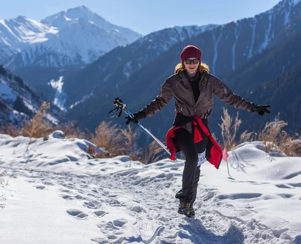 ALMATY, KAZAKHSTAN - APRIL 09, 2017: Amateur competitions - Mountain half-marathon, in the foothills of Almaty, on the Yunat lakes. Young woman jogging outside in sunny winter mountains — Stock Photo, Image