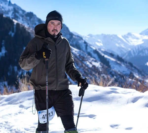 ALMATY, KAZAKHSTAN - 09 APRILE 2017: Concorsi amatoriali - Mezza maratona di montagna, ai piedi di Almaty, sui laghi di Yunat. .Athlete uomo in esecuzione con le montagne in inverno — Foto Stock