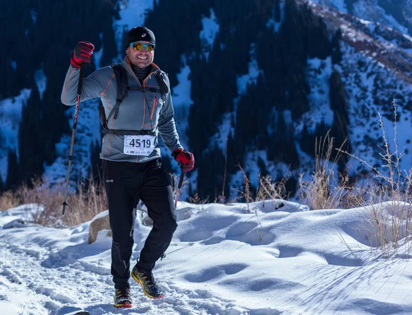 ALMATY, KAZAKHSTAN - 09 DE ABRIL DE 2017: Competiciones de aficionados - Media maratón de montaña, en las estribaciones de Almaty, en los lagos de Yunat. .Athlete hombre corriendo con montañas en invierno — Foto de Stock