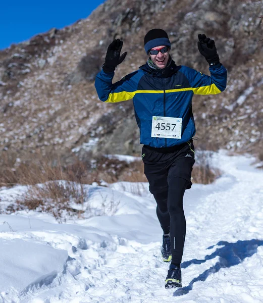 ALMATY, KAZAKHSTAN - 09 DE ABRIL DE 2017: Competiciones de aficionados - Media maratón de montaña, en las estribaciones de Almaty, en los lagos de Yunat. .Athlete hombre corriendo con montañas en invierno — Foto de Stock