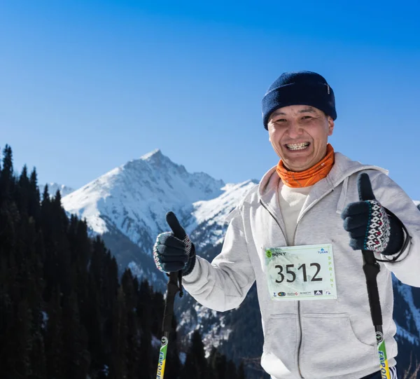 ALMATY, KAZAKHSTAN - 09 APRILE 2017: Concorsi amatoriali - Mezza maratona di montagna, ai piedi di Almaty, sui laghi di Yunat. .Athlete uomo in esecuzione con le montagne in inverno — Foto Stock