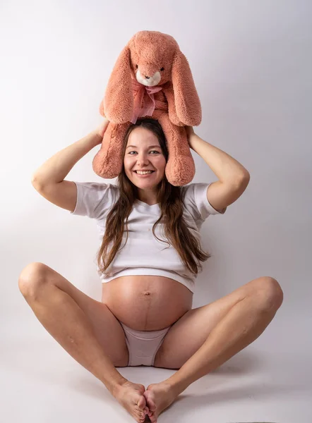 Close-up mulheres grávidas barriga com brinquedo de lebre. Uma bela mulher grávida. Conceito de gravidez, paternidade, preparação e expectativa . — Fotografia de Stock