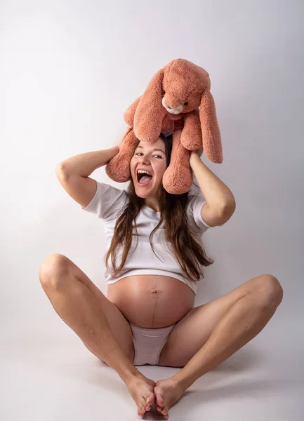 Tavşan oyuncağıyla hamile kadınların göbeğine yakın çekim. Güzel hamile kadın. Hamilelik, ebeveynlik, hazırlık ve beklenti konsepti. — Stok fotoğraf