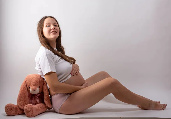 Młoda kobieta w ciąży siedzi na białym tle — Zdjęcie stockowe