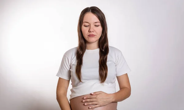 La joven mujer embarazada hermosa experimenta emociones fuertes sobre un fondo blanco — Foto de Stock