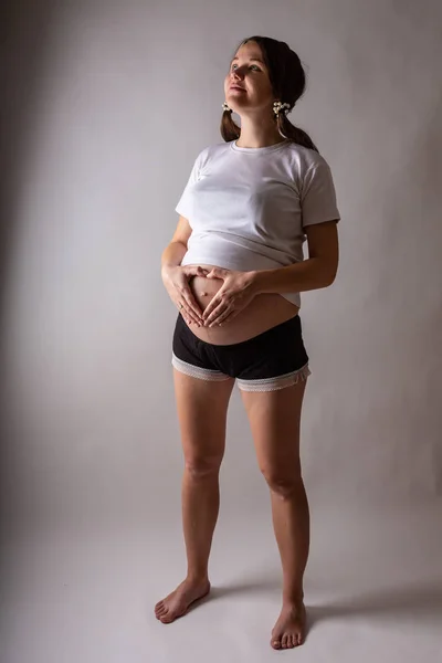 Беременная женщина трогает живот крупным планом в студии — стоковое фото