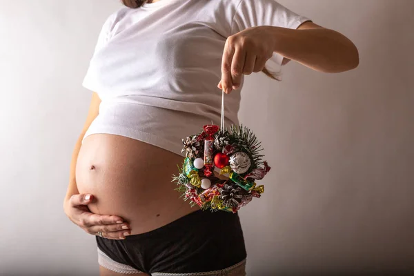 Femme enceinte souriante, touchant son ventre, debout au-dessus du mur blanc. Espace de copie. Noël, Nouvel An concept . — Photo
