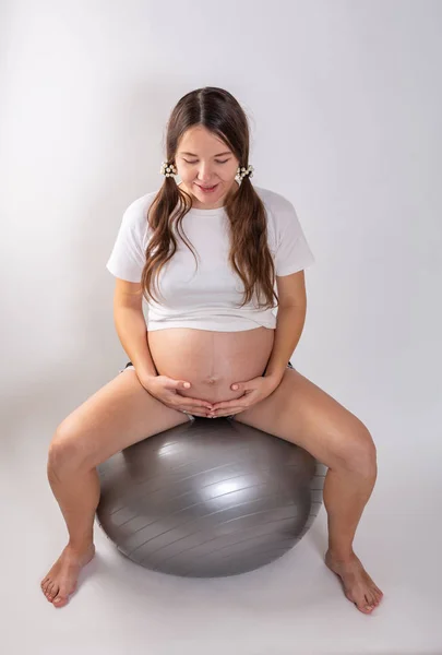 Беременная молодая женщина занимается фитболом — стоковое фото