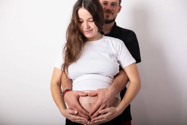 Abgeschnittenes Bild der schönen schwangeren Frau und ihres hübschen Mannes, der den Bauch umarmt — Stockfoto