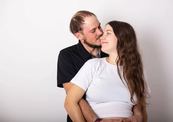 Hombre guapo está escuchando a sus hermosas esposas embarazadas barriga y sonriendo — Foto de Stock