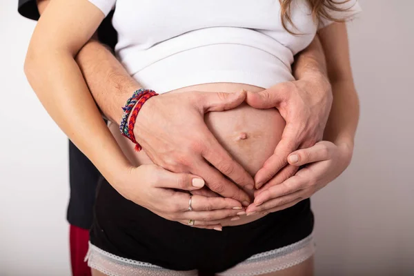 Abgeschnittenes Bild der schönen schwangeren Frau und ihres hübschen Mannes, der den Bauch umarmt — Stockfoto