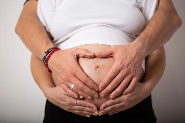 Bijgesneden afbeelding van mooie zwangere vrouw en haar knappe man de buik knuffelen — Stockfoto