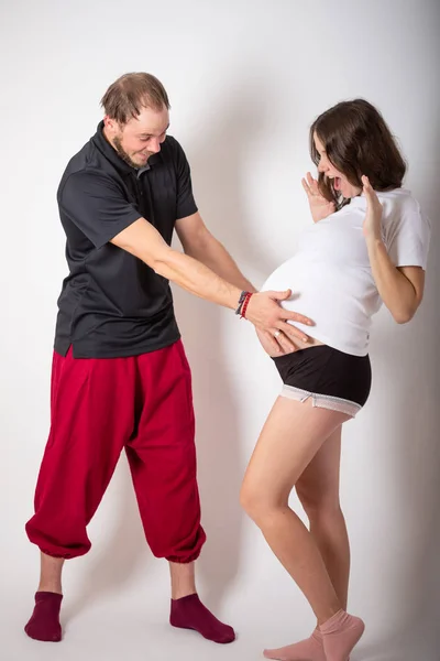 Snygg man lyssnar på sin vackra gravida fru magen och ler — Stockfoto