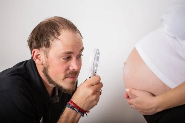 Bonito homem está ouvindo sua bela mulher grávida barriga e sorrindo — Fotografia de Stock
