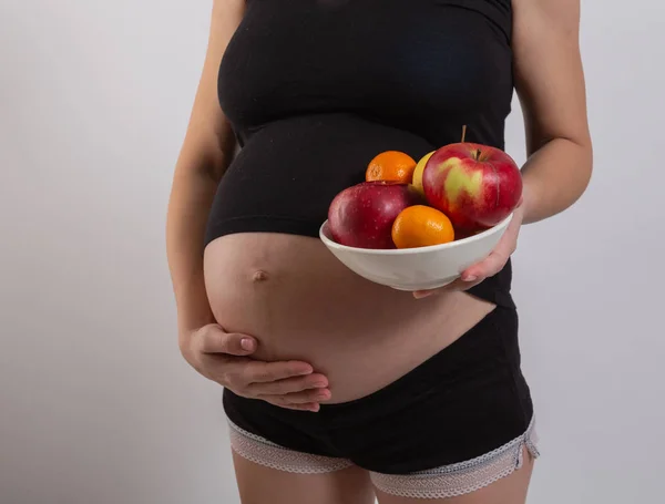 Schwangerschaft und gesunde biologische Ernährung. Schwangere hält frische Vitaminfrüchte in der Hand, Freiraum. Platz für Text. Konzept der Erwartung und Gesundheit. — Stockfoto