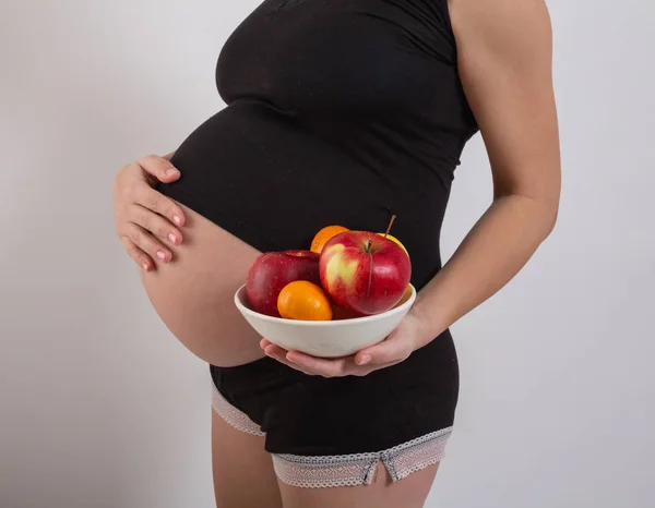 Schwangerschaft und gesunde biologische Ernährung. Schwangere hält frische Vitaminfrüchte in der Hand, Freiraum. Platz für Text. Konzept der Erwartung und Gesundheit. — Stockfoto